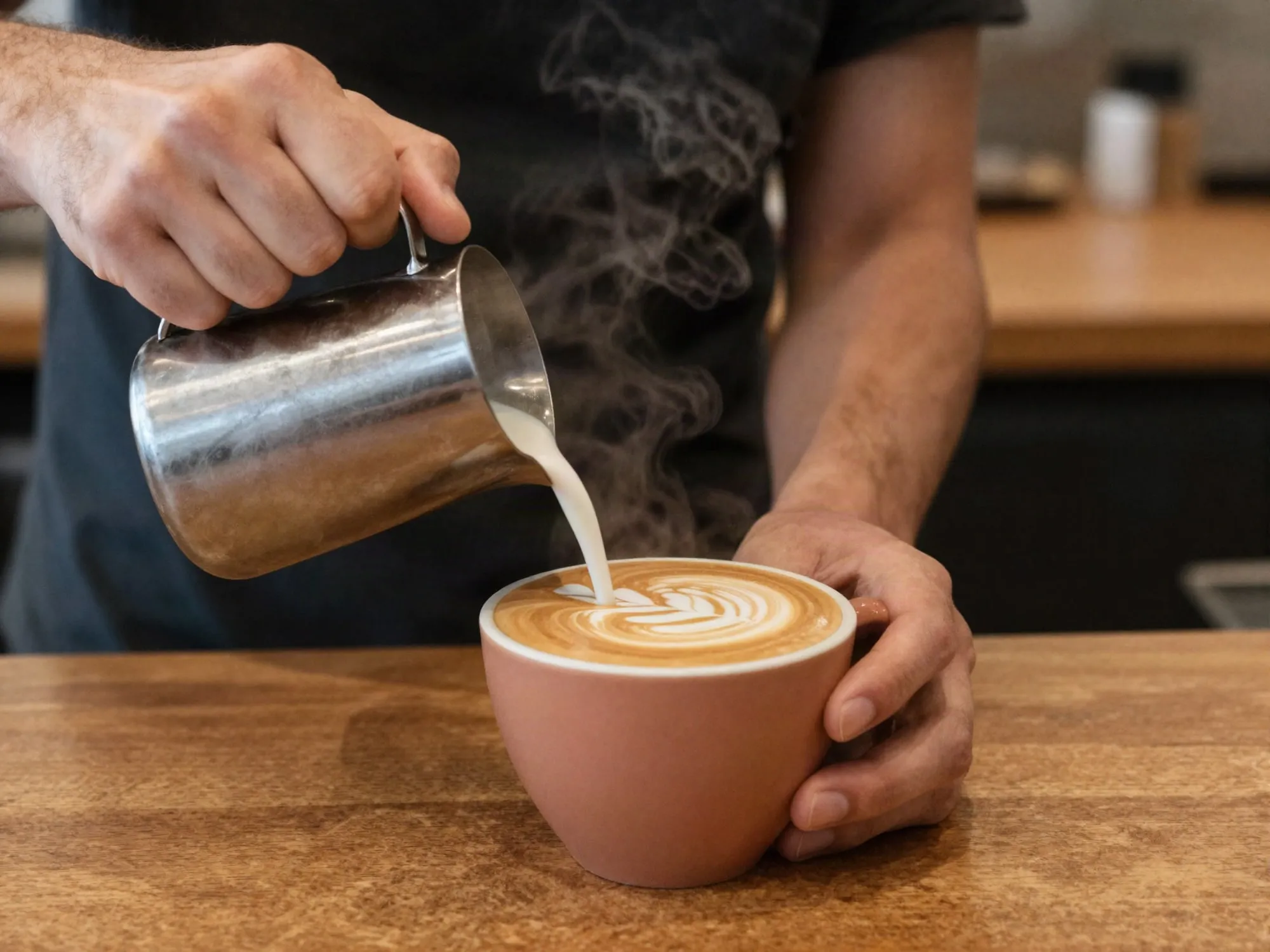 Barista toprak renkli fincana latte art yaparak süt döküyor